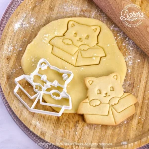 Pâte sablée découpée avec un emporte-pièce Bakers'Tricks et biscuit sablé en forme de chat dans son carton.