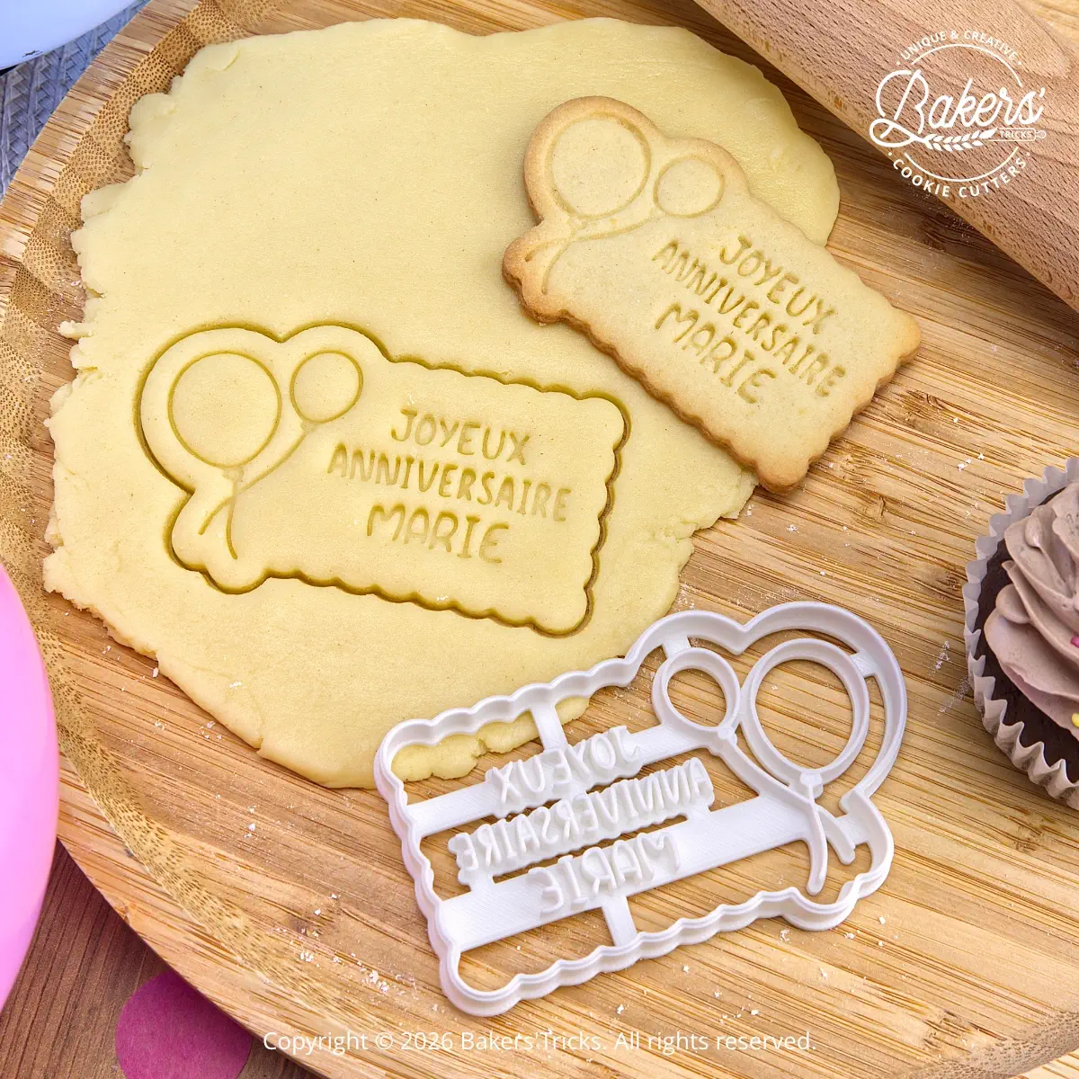 Personalized “Joyeux Anniversaire” cookie cutter with custom name and balloons, shown with cut-out cookie dough before baking and the finished birthday cookie.