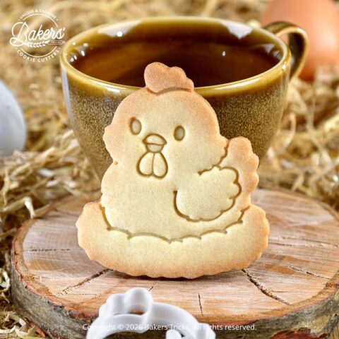 Biscuit poule de Pâques réalisé avec un emporte-pièce Bakers'Tricks, biscuit sablé croustillant posé devant une tasse dans une ambiance de ferme
