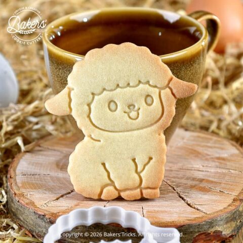 Biscuit mouton de Pâques réalisé avec un emporte-pièce Bakers'Tricks, biscuit sablé doré présenté devant une tasse dans une mise en scène rustique