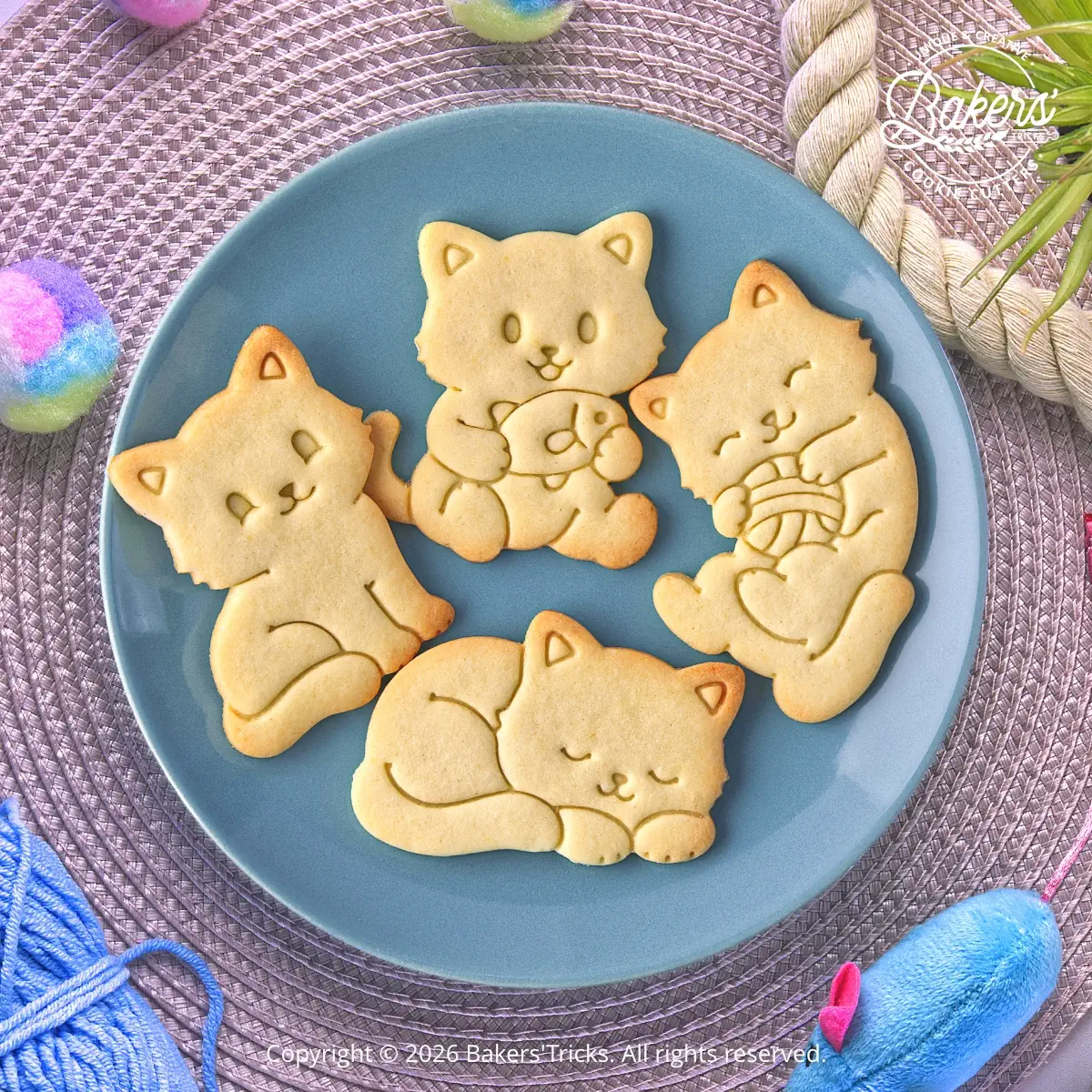 Quatre biscuits sablés en forme de chats réalisés avec les emporte-pièces Bakers'Tricks : chat assis, chat endormi, chat avec son poisson et chat avec sa pelote de laine.