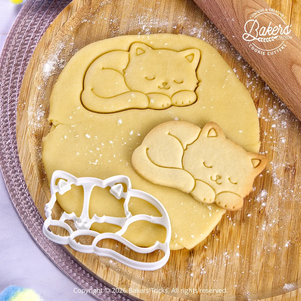 Bakers'Tricks® Sleeping Cat Cookie Cutter shown cutting cookie dough with the finished cookie beside it.